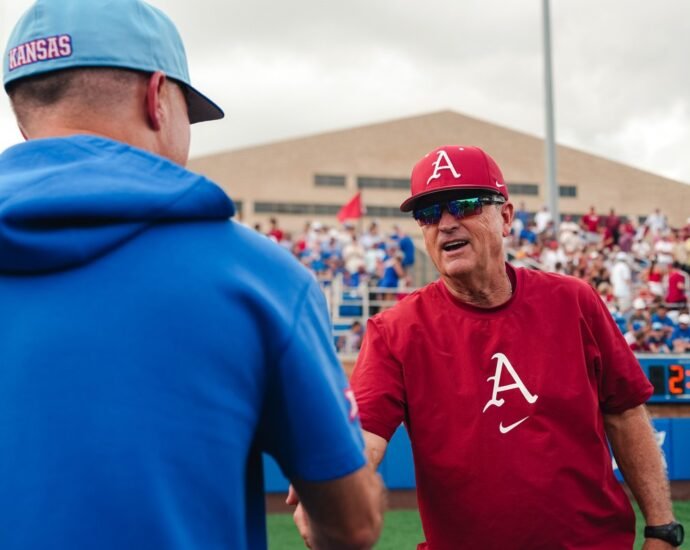 Arkansas coach Dave Van Horn shakes hands with Kansas coach Dan Fitzgerald.